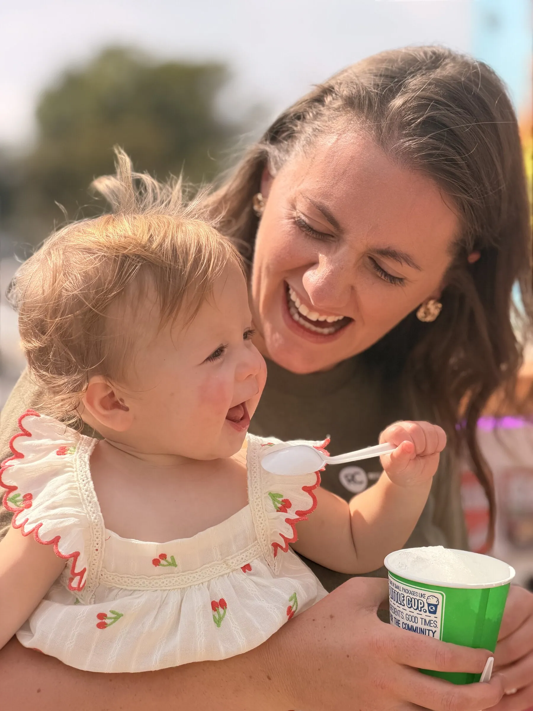 A smiling mom sharing ice cream with her baby girl