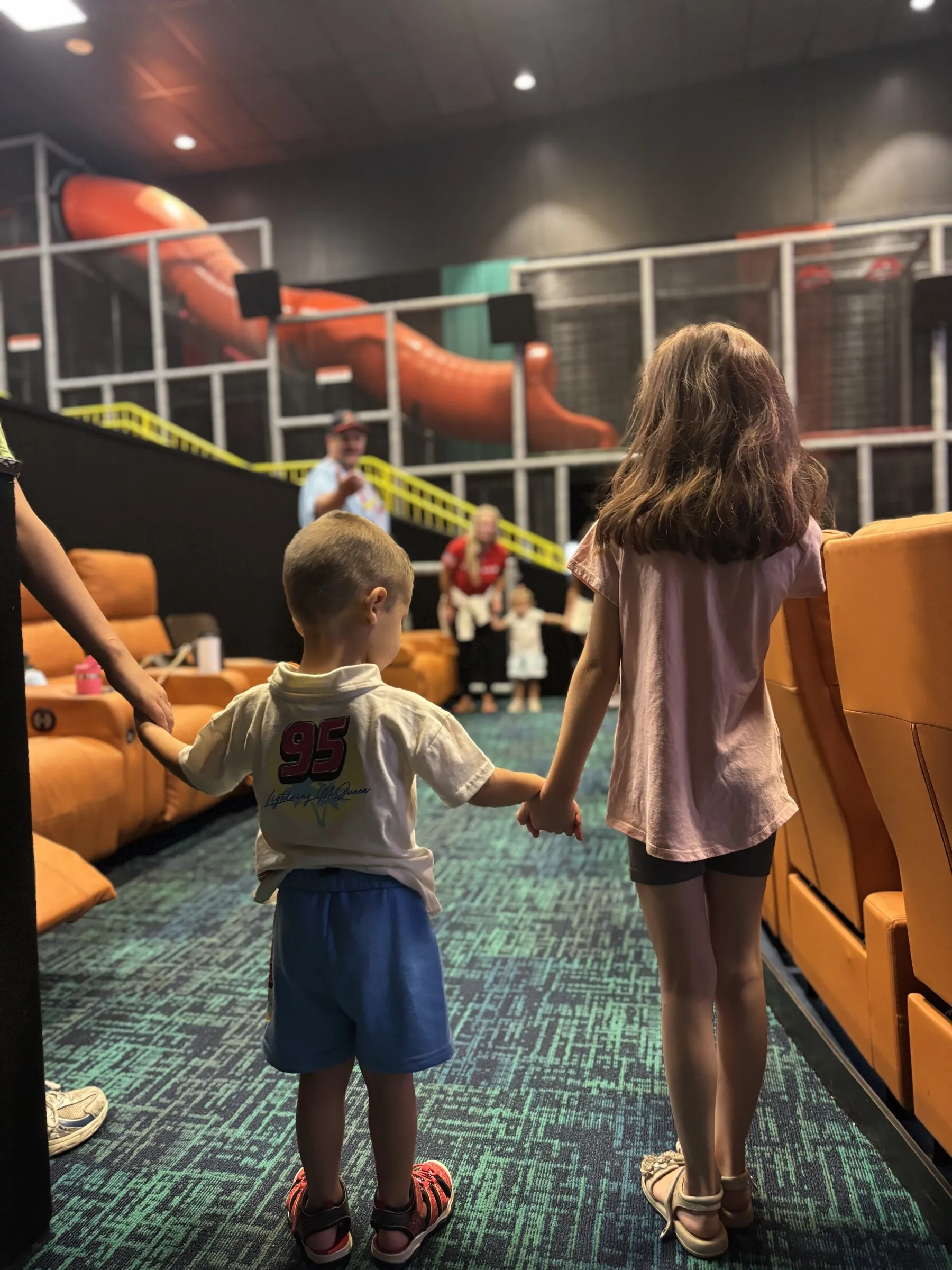 Two kids holding hands walking into the theater