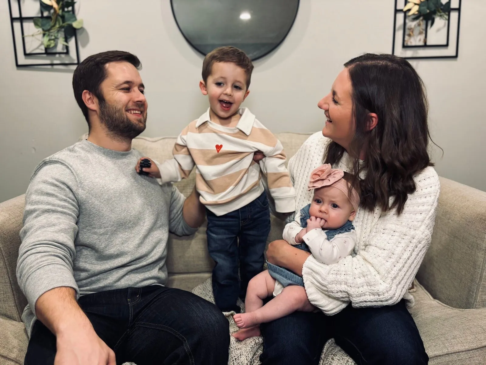 Pastors Luke and Laura Simpson laughing with their son and baby daughter on the couch