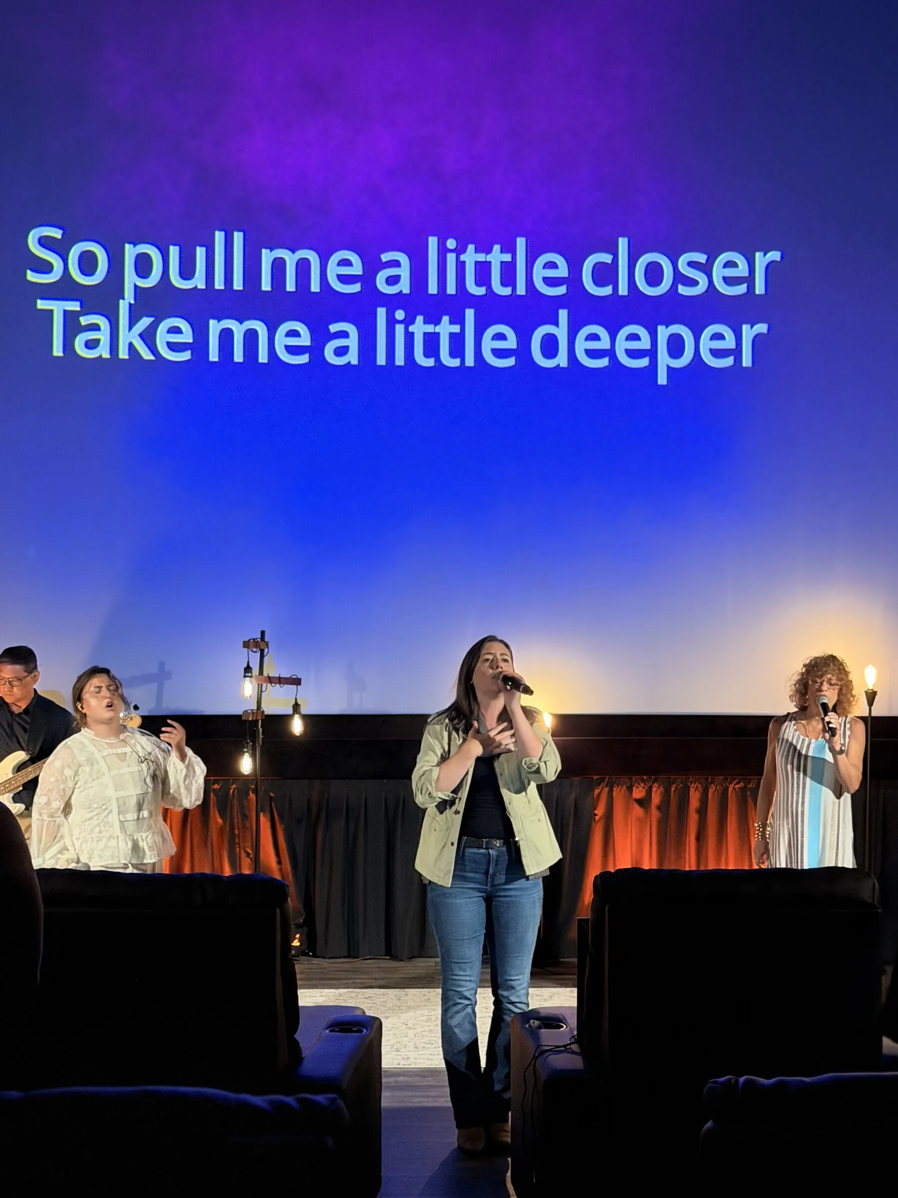 The worship team leading a song on stage with lyrics glowing on the screen